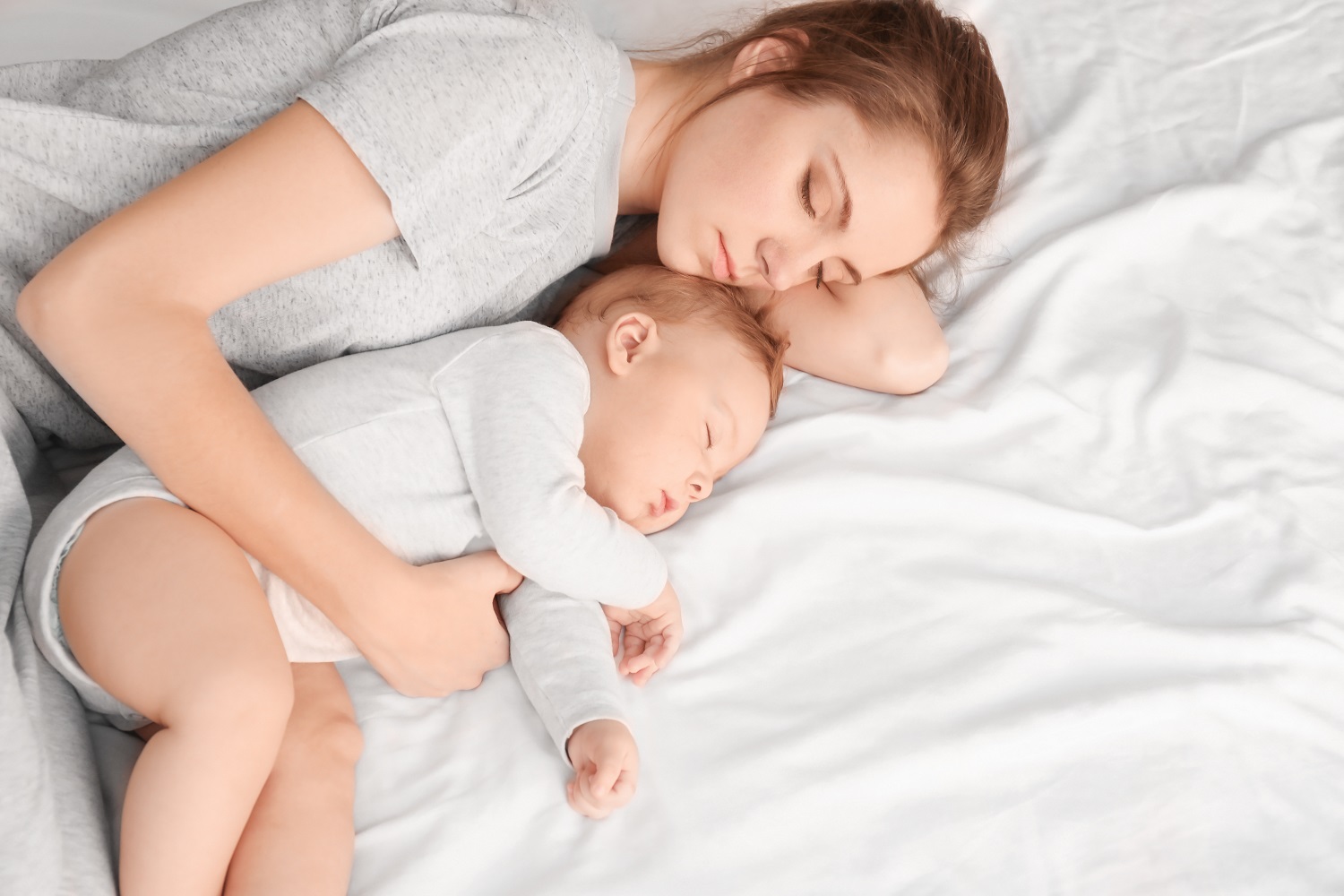 Mother with her baby sleeping on bed at home