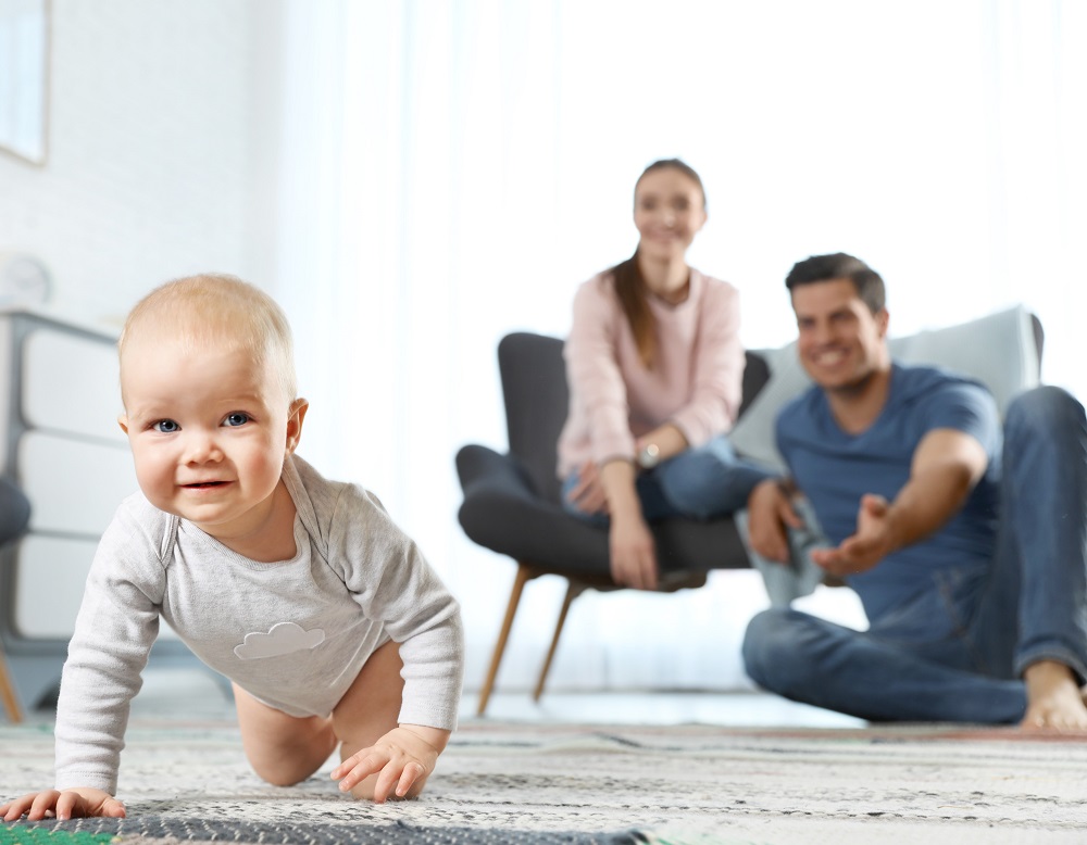 Adorable little baby crawling near parents at home